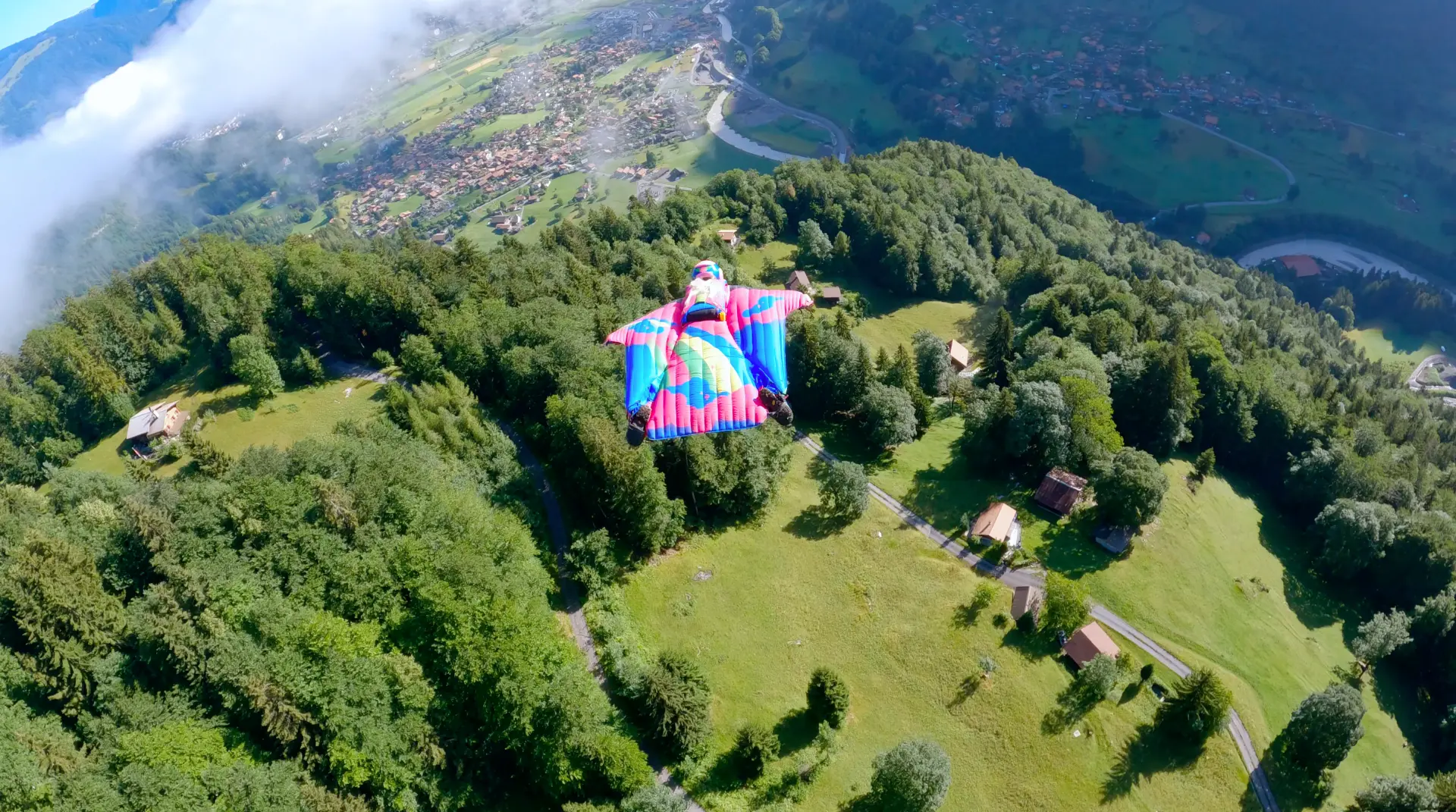Amelia flying a wingsuit above a forested valley