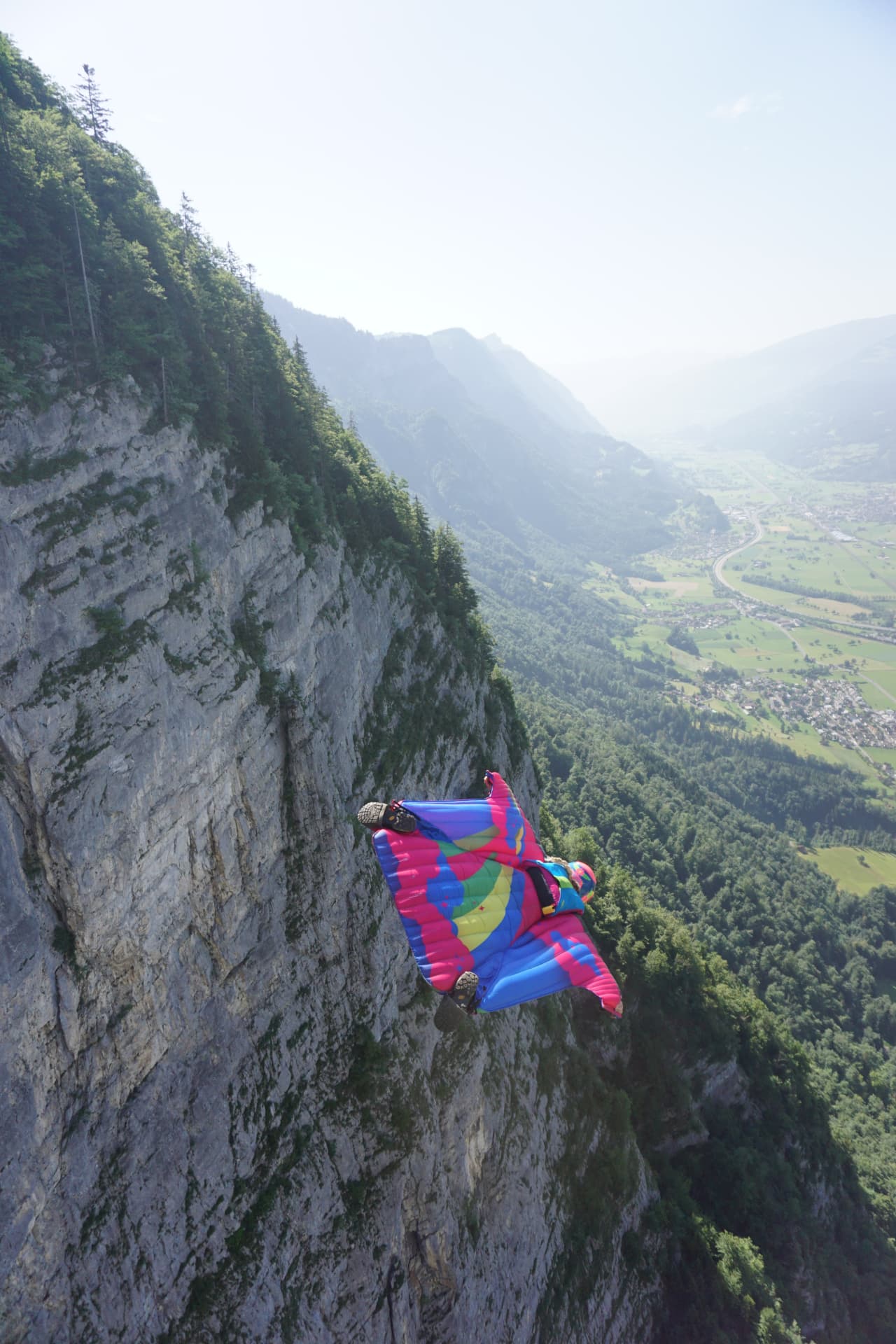 Amelia in a wingsuit soaring past a mountain cliff